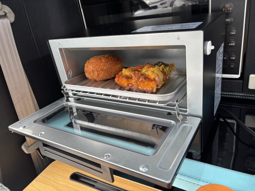 軽キャンの車内でトースターを使用してパンを温めている様子